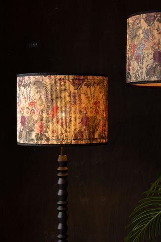 Close-up of the Bamboo Floral Print Easyfit Lampshade styled on a floor lamp that is switched on, with another styled as a pendant shade, next to a plant in the corner of the shot.