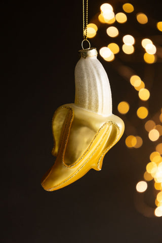 The Banana Christmas Tree Decoration hanging in front of a dark background with fairy lights.