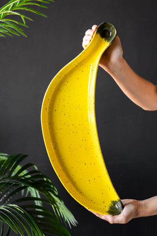 Large yellow speckled banana serving plate being held in someones hands to show the size of the piece.