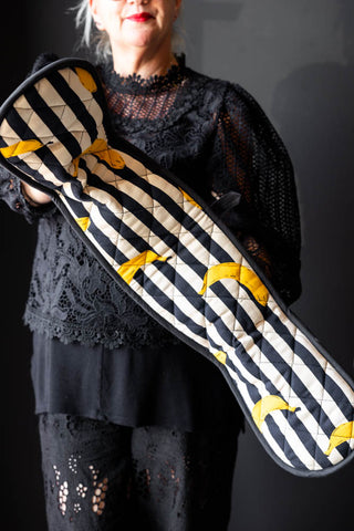 The Banana Black & White Stripe Oven Gloves being modelled in front of a black background.