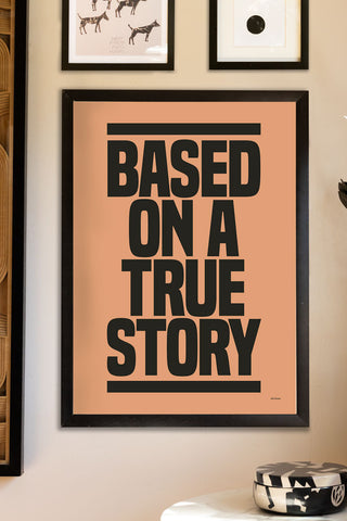 The Based On A True Story Art Print - Unframed, displayed in a frame on a neutral wall with other art prints, above a table with a trinket box on.