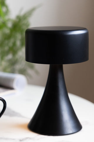 Close-up of the Battery-Powered Cordless Table Lamp In Black on a round white table.