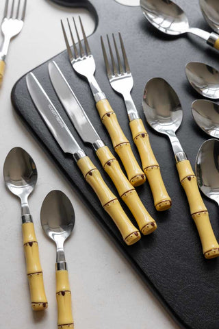 The Beautiful 16-Piece Bamboo Design Cutlery Set displayed on a black serving board on a table.
