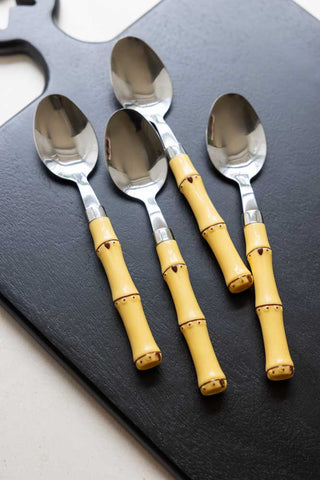 The spoons from the Beautiful 16-Piece Bamboo Design Cutlery Set, displayed on a black serving board.
