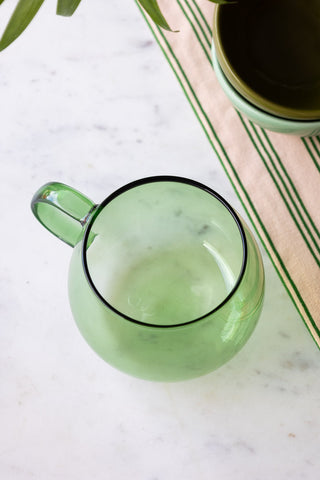 The Gorgeous Green Glass Mug styled on a marble table, seen from above.