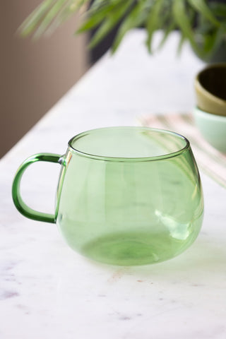 The Gorgeous Green Glass Mug styled on a white table.