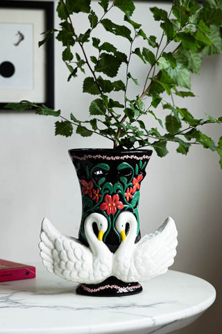 The Beautiful Swan Vase styled on a table with greenery inside.