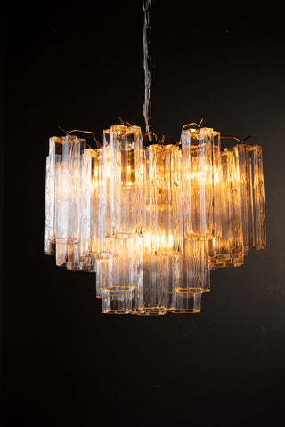 The Beautiful Waved Glass Chandelier in Clear switched on, displayed in front of a black wall.