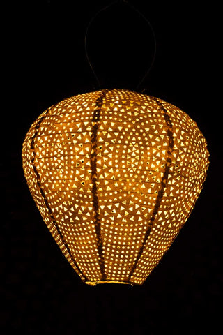 The Bell Shaped Peach Outdoor Garden Lantern hanging in the dark illuminated.