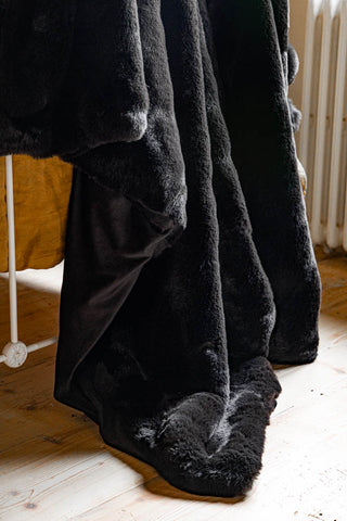 Close-up of the Black Faux Fur Throw draped across the end of a bed.