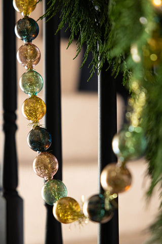 The Black, Green & Gold Bauble Garland styled on a styled stairs with greenery