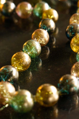 Detail shot of the Black, Green & Gold Bauble Garland styled on a dark surface.