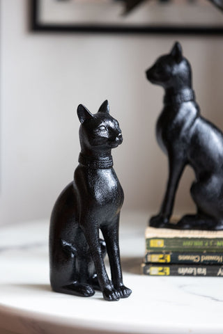 The Black Sitting Cat Bookends styled separately on a table, with one sitting on some books.