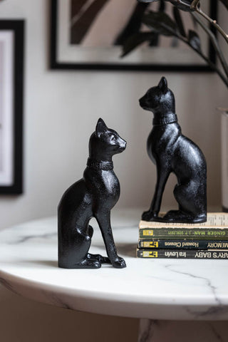 The Black Sitting Cat Bookends on a table facing opposite directions, styled with books and a plant.