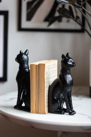 The Black Sitting Cat Bookends styled on a table with some books.