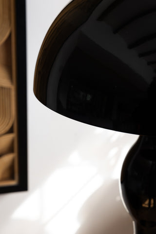 Close-up of the shade of the Black Wavy Retro Floor Light, with a framed artwork on the white wall in the background.