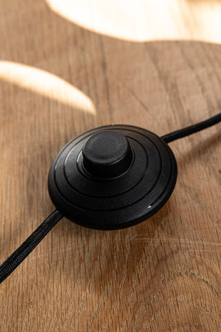 Close-up of the switch on the Black Wavy Retro Floor Light, displayed on a wooden floor.