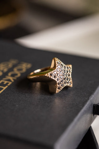 The Black & Gold Studded Star Ring styled on the box.