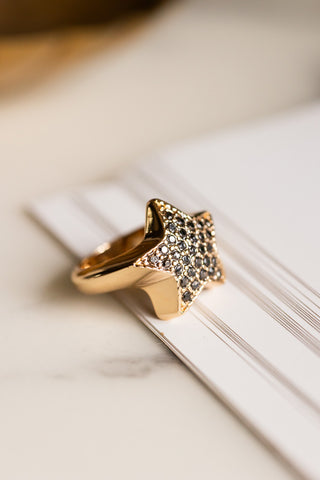 The Black & Gold Studded Star Ring styled on some paper.