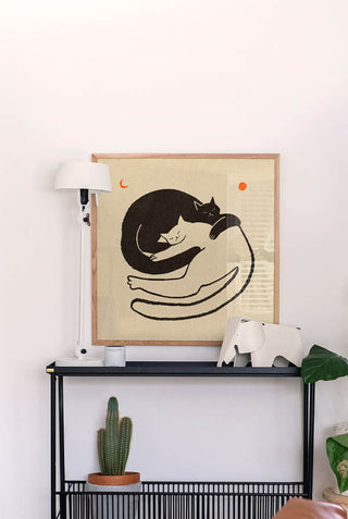 The Cuddling Black & White Cats Art Print hanging on a white hallway wall.