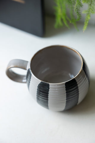 The Black & White Stripe Cuddle Mug on a kitchen worktop, seen from above.