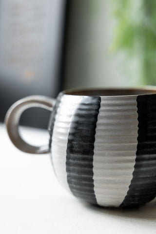 Close-up of the Black & White Stripe Cuddle Mug on a kitchen worktop.