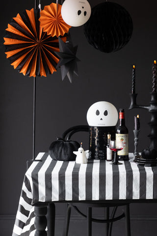 The Black & White Striped Tablecloth styled on a halloween tablescape with various seasonal decorations and tableware.