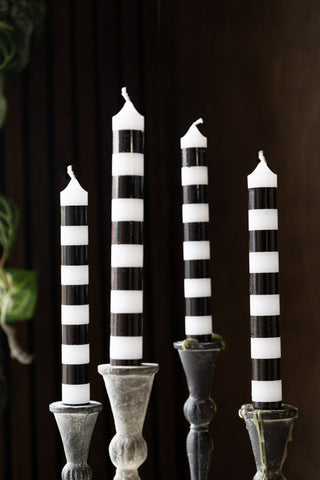 The Black & White Striped Taper Candles - Pack Of 4 displayed in candle holders.