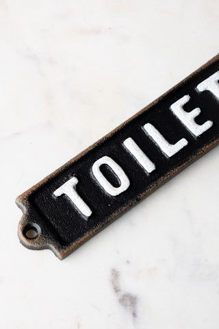 Detail shot of the Black & White Toilet Door Hanging Sign displayed on a white marble surface.