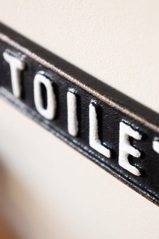 Close-up of the Black & White Toilet Door Hanging Sign displayed on a neutral wall.