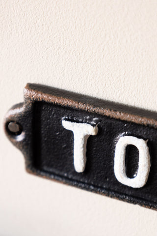 Detail shot of one end of the Black & White Toilet Door Hanging Sign, displayed on a neutral wall.