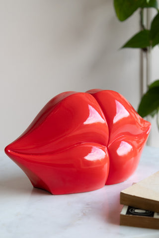 Two halves of bookends fit together in the shape of red lips in a kissing pose.