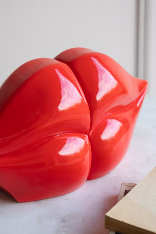 Bold red lips bookend close-up. The lips are puckered like they are about to kiss.