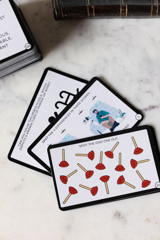 Some of the cards from the Brain Training While You Poo Card Pack displayed on a white marble table.