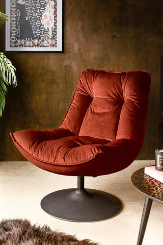 The Burnt Orange Velvet Swivel Chair styled with a rug, coffee table, plant, art print and some accessories.