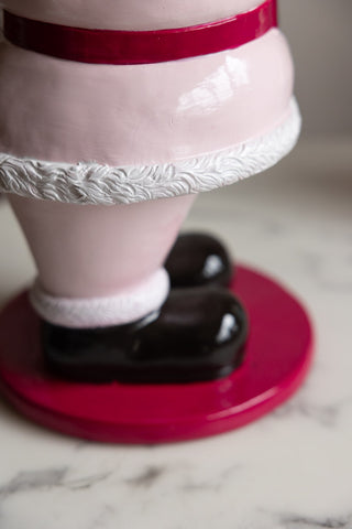 Close-up of the base of the Butler Santa In Pink Christmas Decoration, displayed on a white marble table.