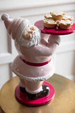 The Butler Santa In Pink Christmas Decoration styled on a small side table.