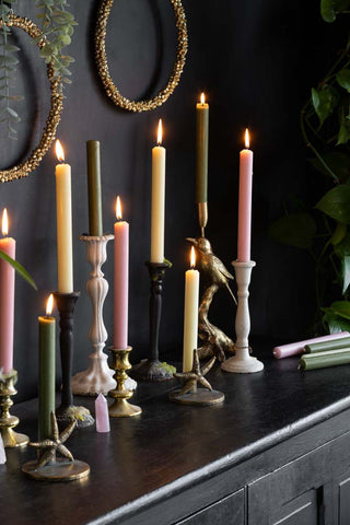 A beautiful display of Christmas dinner candles on a sideboard. The dinner candles are in a mix of colours from pink and ivory to dark green.