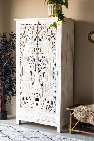 The Carved Bird Design Wood Cabinet styled with plants, a bench, rugs and a mirror.