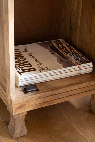 The Carved Floral Design Wood Bedside Table with the door open and magazines inside.