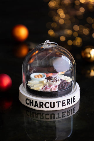 The Charcuterie Dome Christmas Tree Decoration displayed on a black surface with lights in the background.