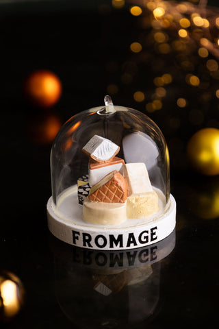 The Cheese Dome Christmas Tree Decoration on a dark surface with lights in the background.