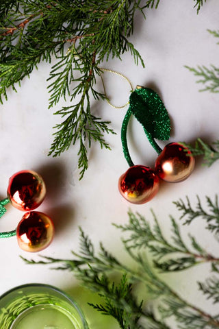 Cherries Christmas Tree Decoration on white marble with greenery