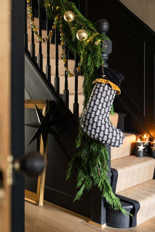 A Lifestyle image of The Luxury Christmas Tree Stocking hanging from some stairs captured through a doorway