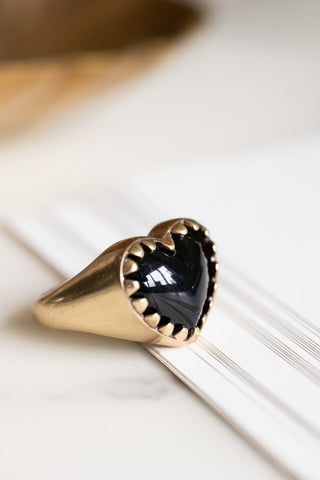 Close-up of the Chunky Gold & Black Heart Ring styled on some paper.