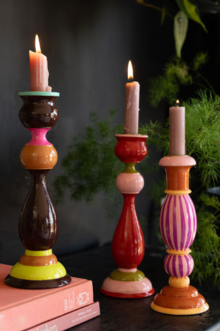 The Colourful Candlestick Holder in Pink Stripes styled with two other colourways, with lit candles inside.