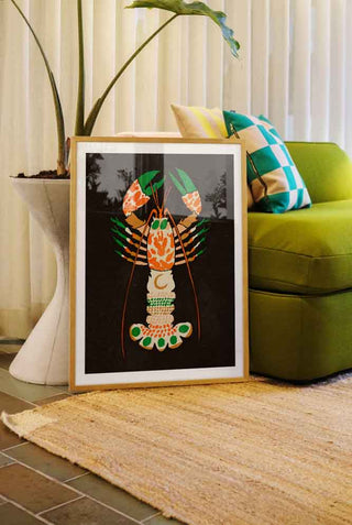 A lobster art print leaning against a green sofa.