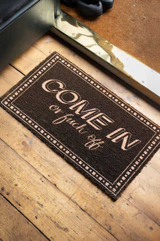 A Lifestyle image of the Come In or Fuck Off Doormat in a hallway