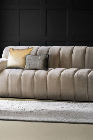 Close-up of the Cream Roll Back 3-Seater Sofa styled with cushions on, with a rug on the floor.