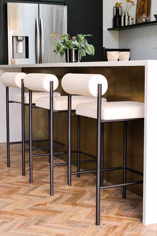 Three of the Cream & Black Faux Leather Roll Back Bar Stools in a kitchen at a breakfast bar.